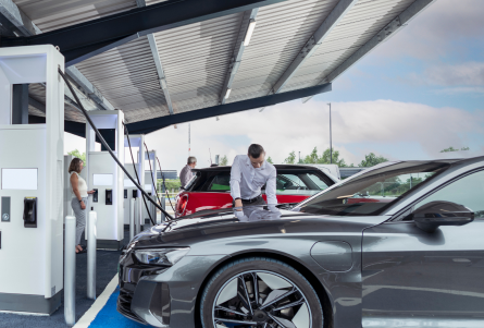 Businessman at rapid charging electric vehicle at motorway services