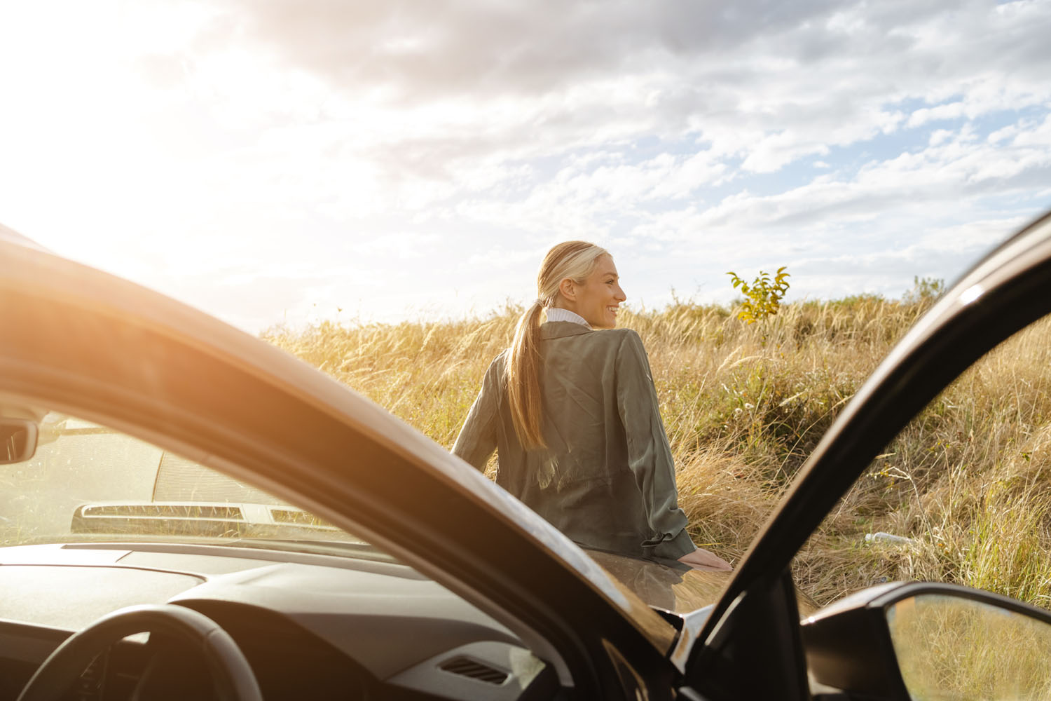 Young female traveller enjoying the sunset outdoors while standing next to the car